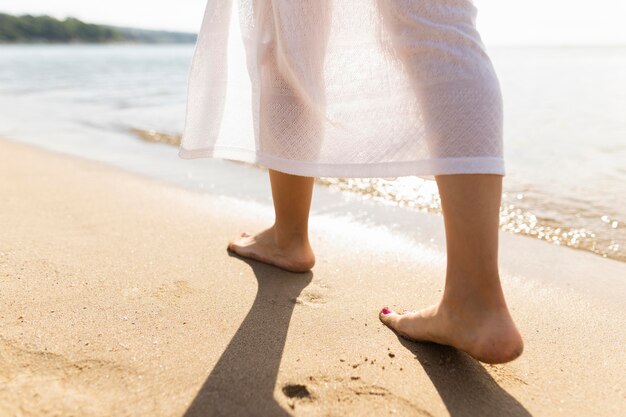 Vista posteriore dei piedi della donna sulla spiaggia di sabbia
