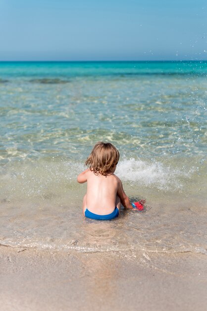 Vista posteriore del bambino seduto sulla riva