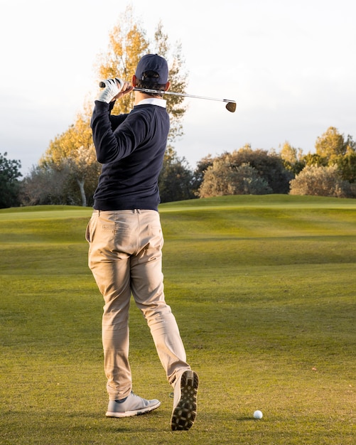 Vista posteriore dell'uomo che gioca sul campo da golf erboso