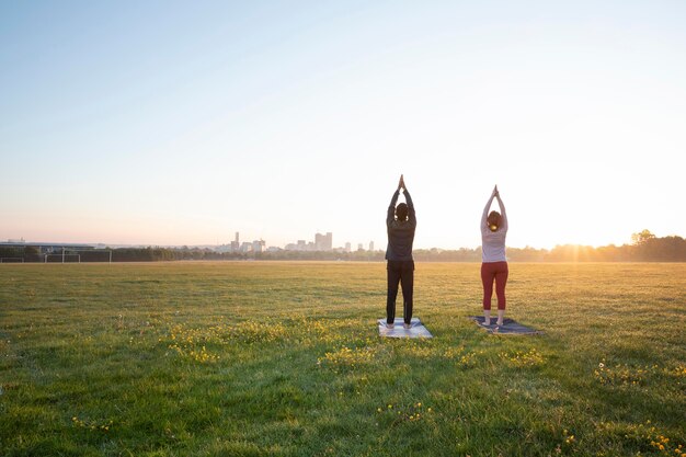 Vista posteriore dell'uomo e della donna che fanno yoga insieme all'aperto