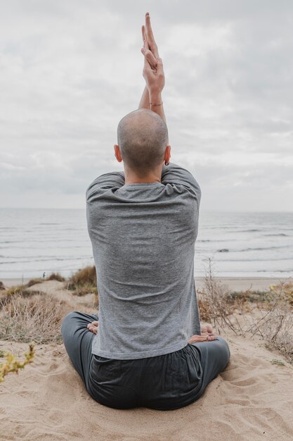 Vista posteriore dell'uomo fuori meditando mentre si fa yoga
