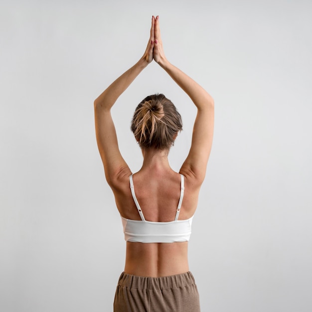 Vista posteriore della donna a praticare yoga a casa