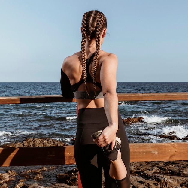 Vista posteriore della donna che si estende sulla spiaggia