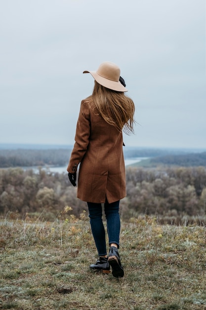 Vista posteriore della donna con il cappello in posa nella natura all'aperto