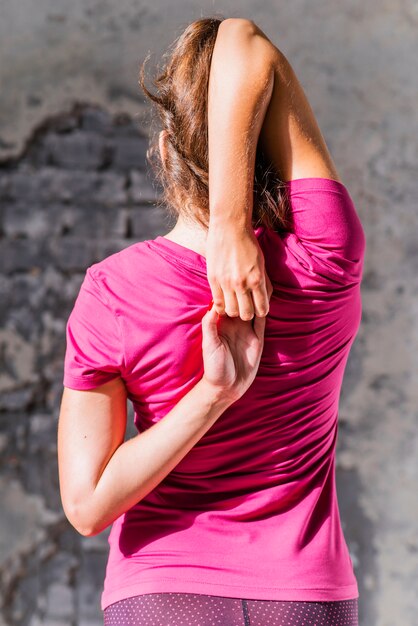 Vista posteriore della donna in forma facendo gomukhasana in classe di yoga