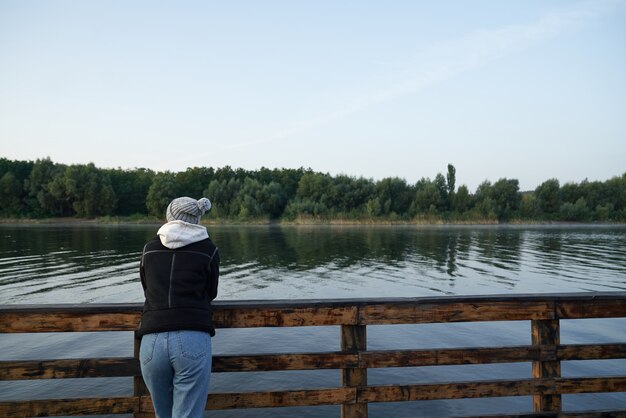 Vista posteriore della donna in piedi molo vicino al lago