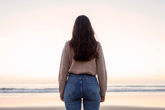 Vista posteriore della donna in posa sulla spiaggia