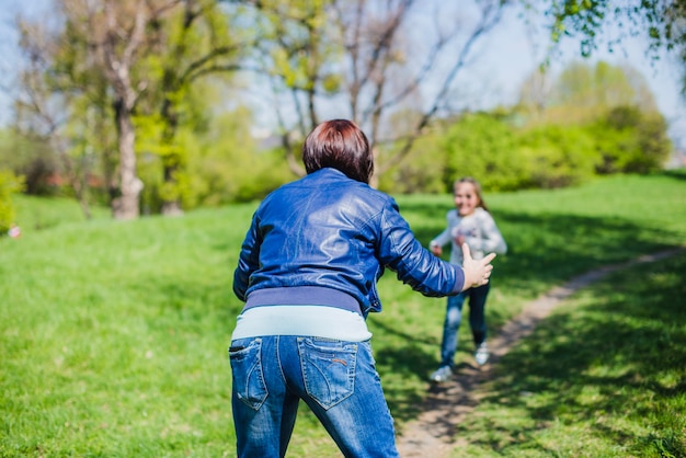 Vista posteriore della madre che gioca con la sua figlia all&#39;aperto