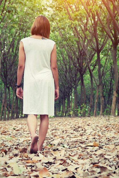 Vista posteriore della ragazza camminare sul terreno coperto di foglie