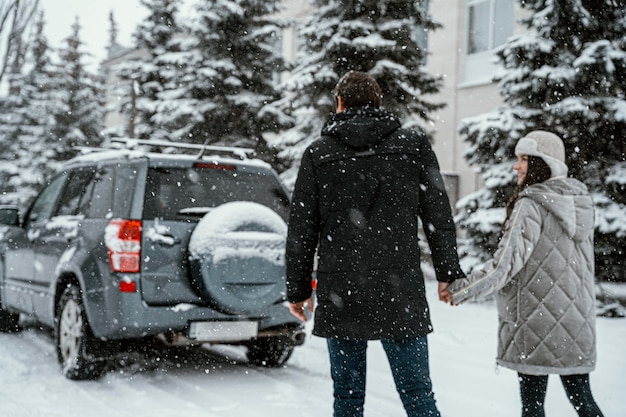 Vista posteriore delle coppie che si godono la neve durante un viaggio in auto