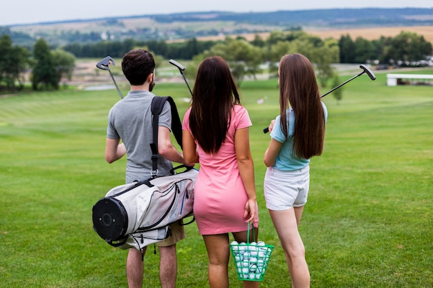 Vista posteriore di amici con attrezzatura da golf