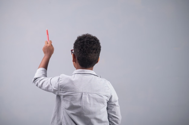 Vista posteriore di un bambino con gli occhiali e una camicia a righe che disegna con una matita