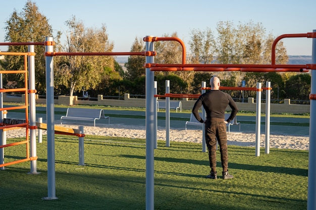 Vista posteriore di un giovane ispanico che si riposa dopo aver lavorato nel campo sportivo