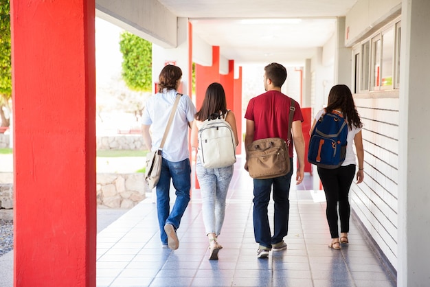 Vista posteriore di un gruppo di studenti universitari che si allontanano in un corridoio scolastico