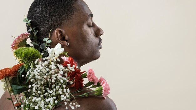 Vista posteriore di un uomo a torso nudo in posa con bouquet di fiori e copia spazio