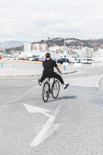 Vista posteriore di un uomo in sella alla bicicletta sulla strada