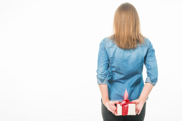 Vista posteriore di una donna con scatola regalo dietro la schiena