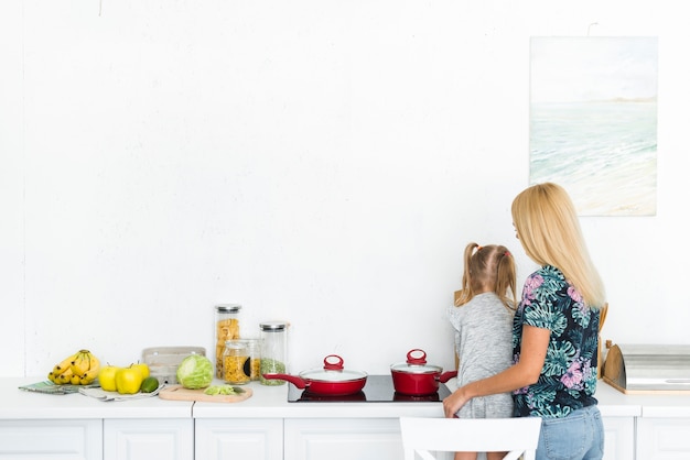 Vista posteriore di una donna con sua figlia in cucina