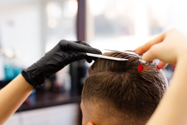 Vista posteriore donna che taglia i capelli del suo cliente