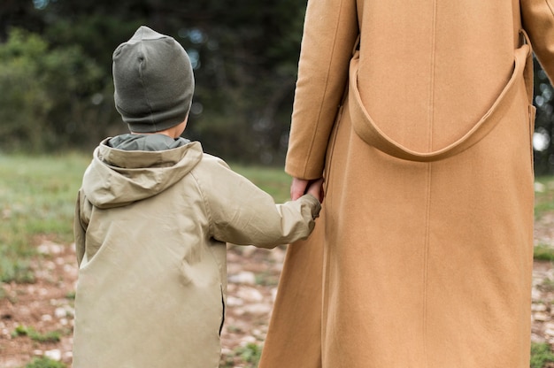 Vista posteriore donna che tiene il suo bambino per mano