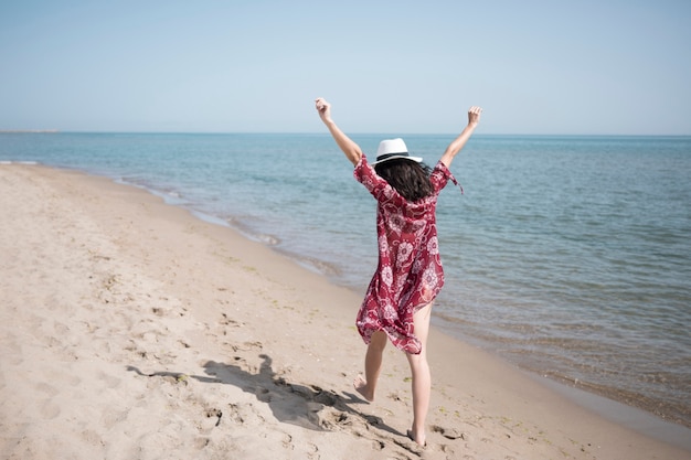 Vista posteriore eccitata donna che cammina in riva al mare