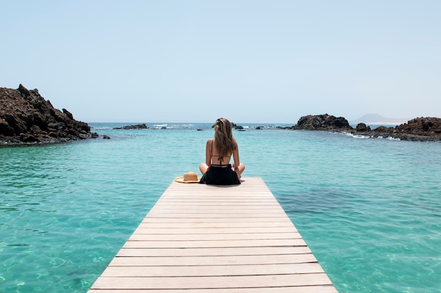 Vista posteriore giovane donna che guarda l'oceano