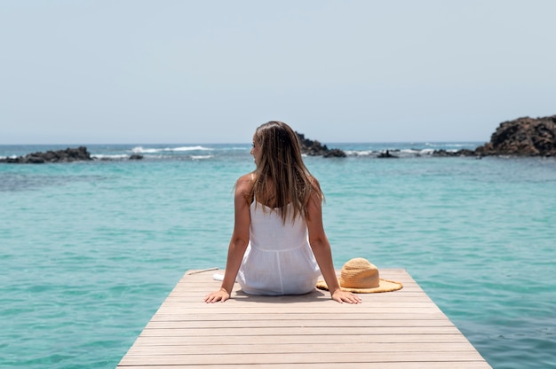 Vista posteriore giovane donna che guarda l'oceano