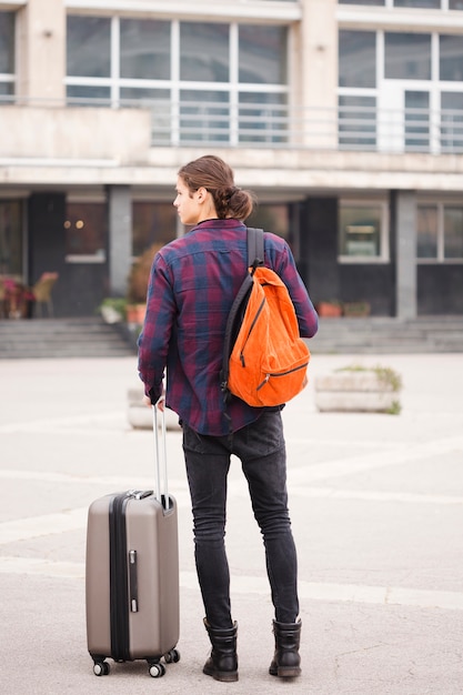 Vista posteriore giovane turista con bagagli