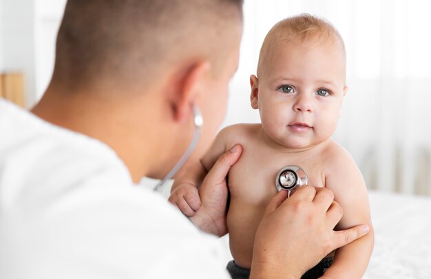 Vista posteriore medico ascolto piccolo bambino con stetoscopio