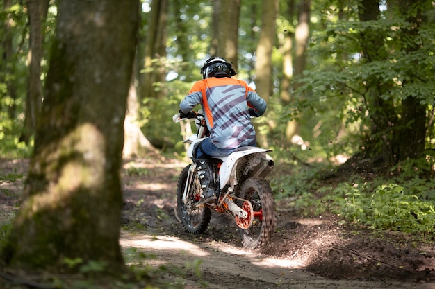 Vista posteriore uomo attivo in sella a una moto nella foresta