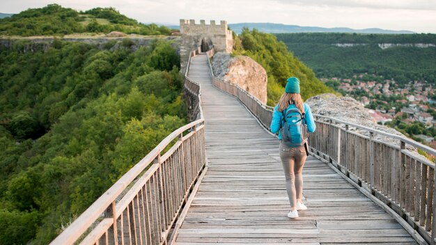 Vista posteriore viaggiatore che cammina lungo il ponte