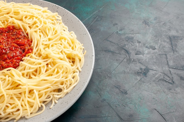 Vista ravvicinata anteriore cotta pasta italiana con carne macinata e salsa di pomodoro sulla superficie blu scuro