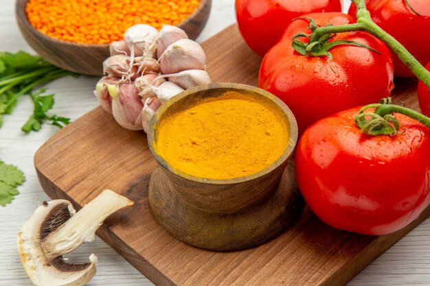 Vista ravvicinata dal basso ramo di pomodoro fresco aglio curcuma sul tagliere funghi sul tavolo grigio