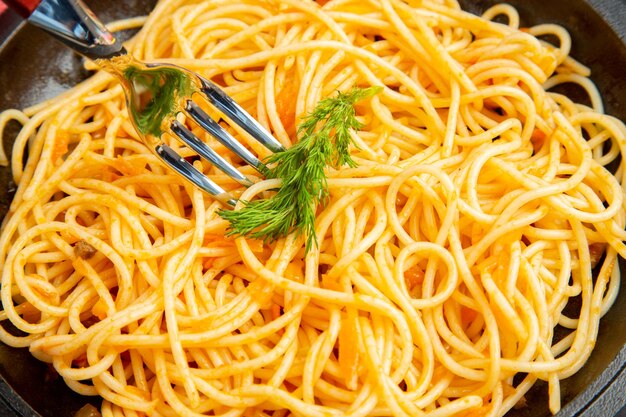 Vista ravvicinata dal basso spaghetti padella tovaglia a quadretti rossa e bianca su sfondo scuro