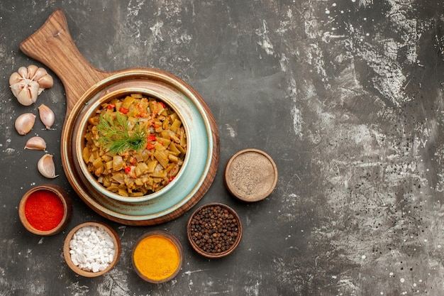 Vista ravvicinata dall'alto appetitoso piatto di fagiolini degli appetitosi fagiolini e pomodori sulla tavola di legno ciotole di spezie aglio sul tavolo scuro