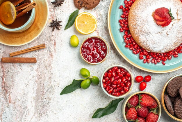 Vista ravvicinata dall'alto bacche e biscotti una tazza di tè con marmellata di limone biscotti al cioccolato la torta