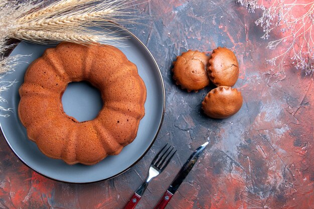 Vista ravvicinata dall'alto cupcakes spighe di grano rami di albero accanto alla forchetta e coltello dei cupcakes della torta