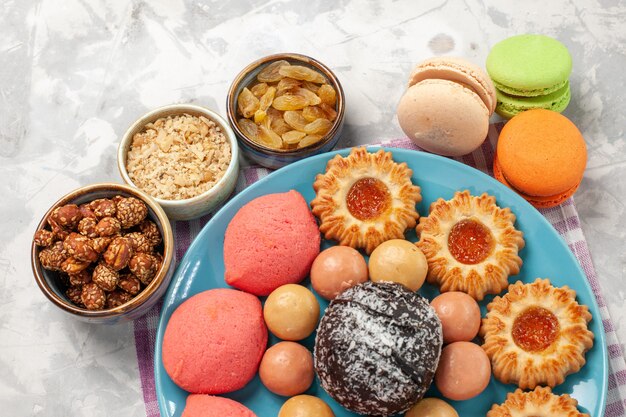 Vista ravvicinata dall'alto deliziose torte con biscotti e macarons sulla scrivania bianca