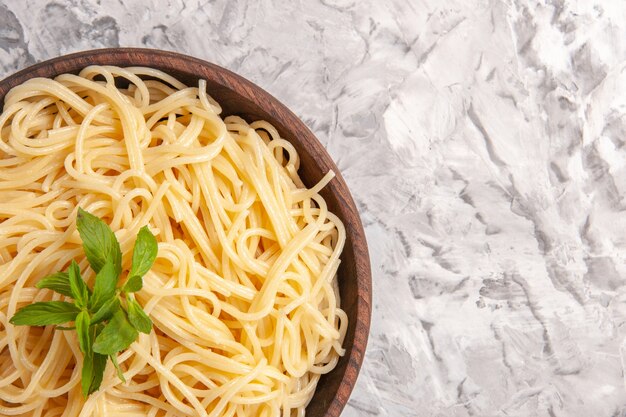 Vista ravvicinata dall'alto deliziosi spaghetti con foglia verde su un piatto da tavola bianco pasta pasto