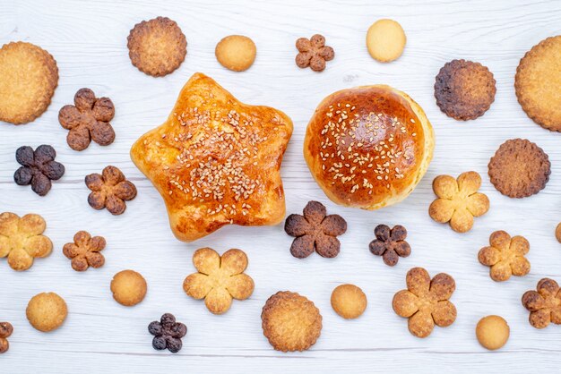 Vista ravvicinata dall'alto di deliziosi biscotti dolci formati diversi insieme a pasticcini al forno sulla scrivania leggera, zucchero dolce biscotto biscotto