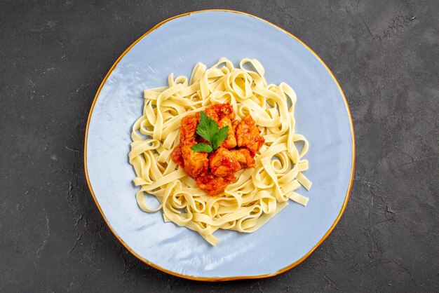 Vista ravvicinata dall'alto pasta con carne appetitosa pasta con carne e sugo sul piatto blu sulla superficie scura