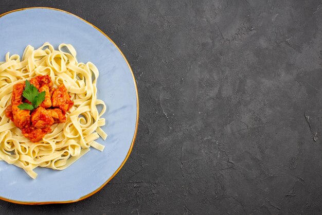 Vista ravvicinata dall'alto pasta con carne blu piatto di pasta appetitosa con sugo e carne sul lato sinistro del tavolo