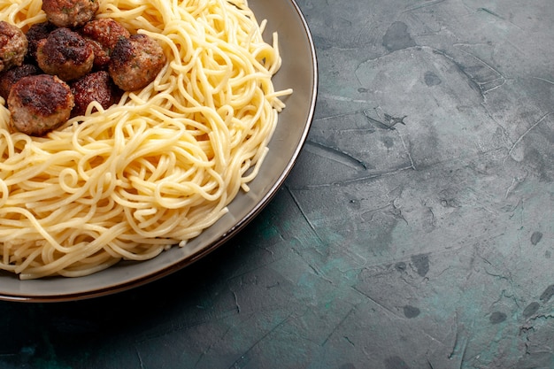 Vista ravvicinata dall'alto pasta italiana cotta con polpette di carne sulla superficie blu scuro