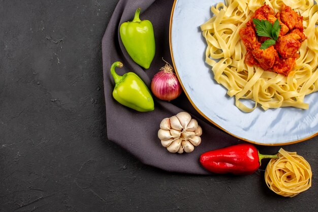 Vista ravvicinata dall'alto pasta pasta palla pepe aglio cipolla accanto alla pasta appetitosa con carne e sugo sulla tovaglia