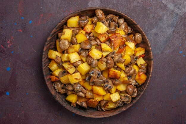 Vista ravvicinata dall'alto patate con funghi patate fritte con funghi fritti in una ciotola di legno su uno sfondo scuro