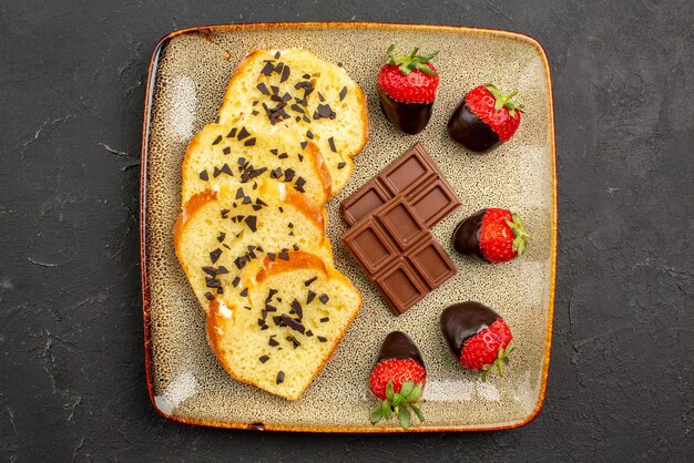 Vista ravvicinata dall'alto pezzi di torta appetitosi pezzi di torta con cioccolato e fragole sul tavolo scuro