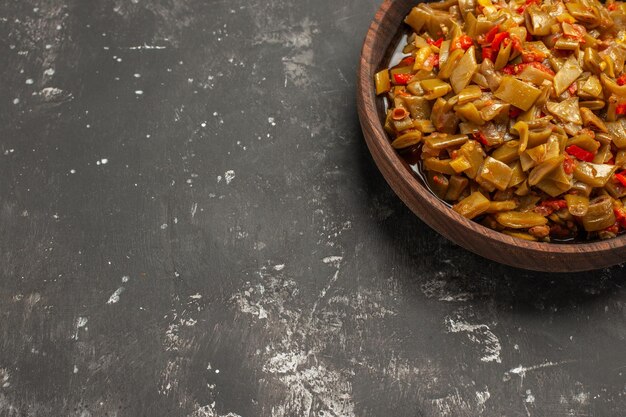 Vista ravvicinata dall'alto piatto appetitoso piatto appetitoso di fagiolini e pomodori in una ciotola sul tavolo scuro