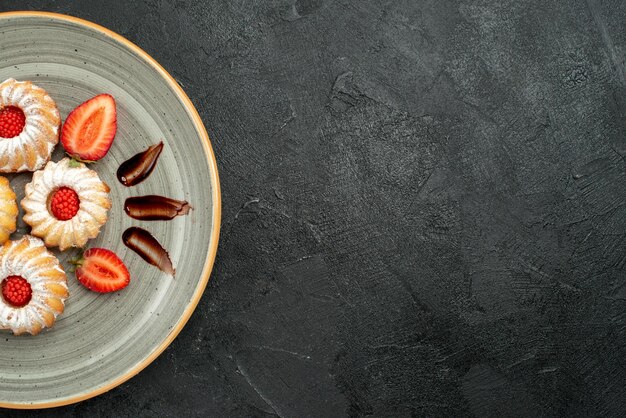 Vista ravvicinata dall'alto piatto di biscotti piatto di biscotti appetitosi con cioccolato e fragola sul lato sinistro del tavolo