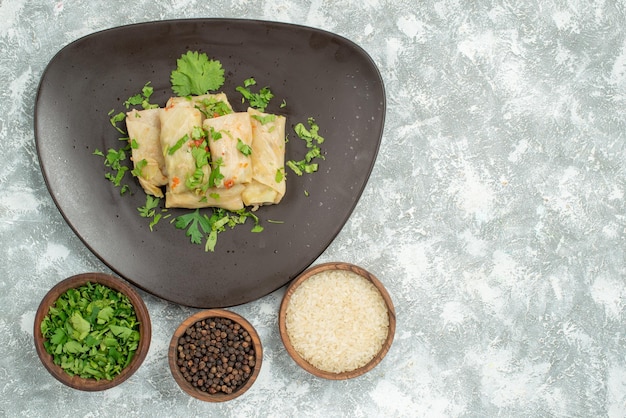 Vista ravvicinata dall'alto piatto di cibo piatto di cavolo ripieno e piatti di riso nero ed erbe aromatiche sul lato sinistro del tavolo