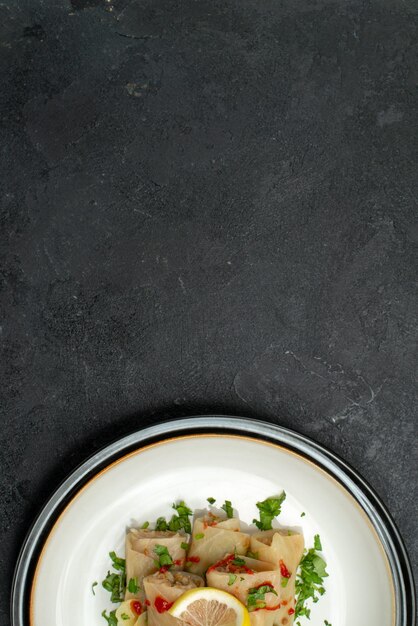 Vista ravvicinata dall'alto piatto di piatto appetitoso piatto appetitoso di cavolo ripieno con erbe limone e salsa su un piatto bianco su superficie nera